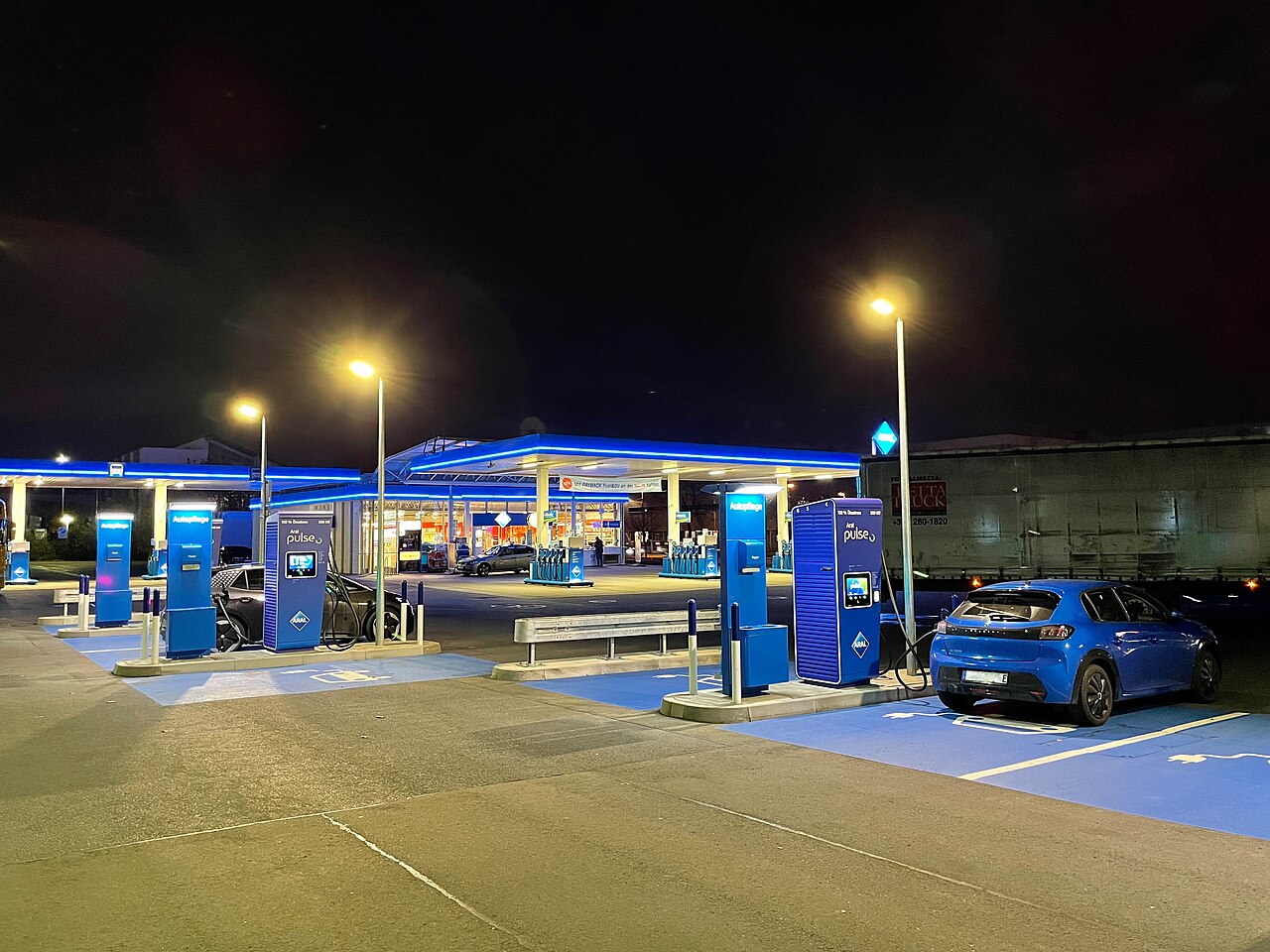 Widok stacji ładowania pojazdów elektrycznych. W tle stacja benzynowa